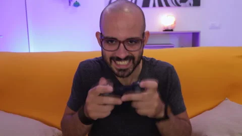 Time lapse: Smiling man plays a video game. Recreation and play time Video stock 136355423