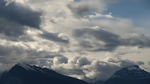 Time lapse of spectacular churning clouds above two mountain peaks in Banff NP Stock Footage 257957558