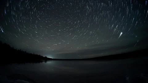 Time lapse with star trails of the night sky above a large calm lake with the Stock Footage 323538840