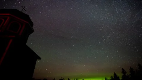 Time lapse of a starry night sky with Aurora along the horizon behind a church Stock Footage 249423871