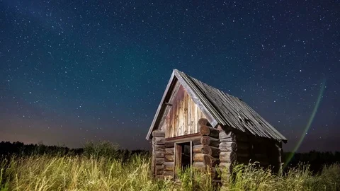 Time lapse of starry sky at the edge of the forest with cabin log house in the Stock Footage 75324881