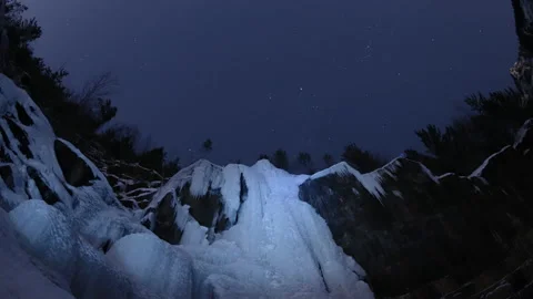 Time lapse of starry sky over the frozen waterfall in the Siberian forest.  Video stock 88982352