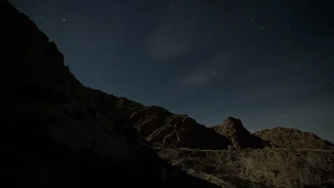 Time lapse of stars and thin clouds over rocky mountains Stock Footage 329863481