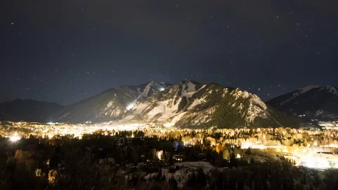 Time-lapse of stars moving over a city and snowy mountains at night Stock Footage 113200437
