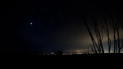 Time lapse of stars setting beyond a distant small town Stock Footage 126833098