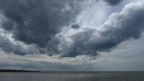 Time-lapse of storm clouds drifting across the sky above a large lake with trees Stock Footage 340240198