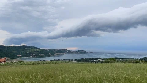 Time lapse of storm clouds running across the sky against the sea, green hills Video stock 155071382