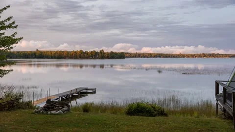 Time lapse of storm clouds turning into a colourful sunset reflecting in a lake Stock Footage 317786538