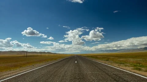 Time lapse of straight road, cloudy sky and mountains against backdrop Stock Footage 51497145