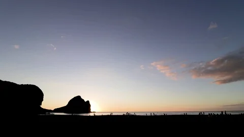 Time lapse of sun going down on Piha beach with people on the beach. Stock Footage