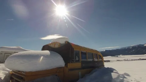 Time-lapse of sun moving over old schoolbus in snow covered field Stock Footage 73051170