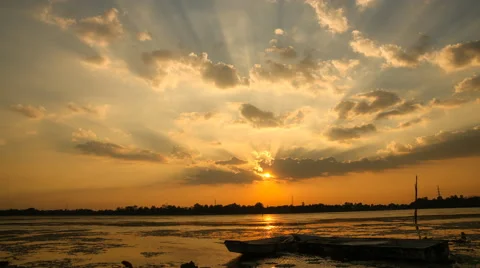 Time lapse of sun rays emerging through the clouds tilt down to local river Stock Footage 50377549