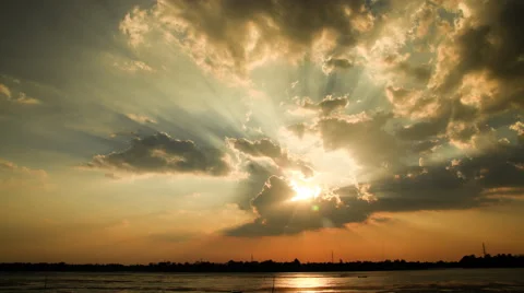 Time lapse of sun rays emerging through the clouds tilt down to local river Stock Footage 50400132
