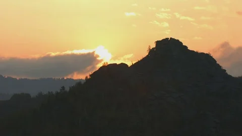Time lapse of sun rising out of rocky hill through clouds Stock Footage 78589452
