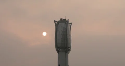 Time lapse of sun rising through foggy gray clouds behind chimney of factory Video stock 73881391