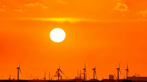 Time-lapse of the sun setting behind electric windmills Stock Footage 108992656