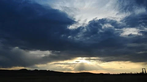 Time lapse as the sun is setting behind dark blue early evening clouds Stock Footage 280357492