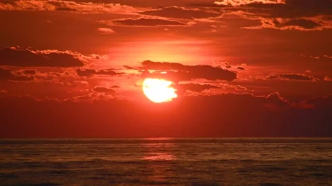 Time lapse of sun setting over the ocean with orange sky Stock Footage 156404408