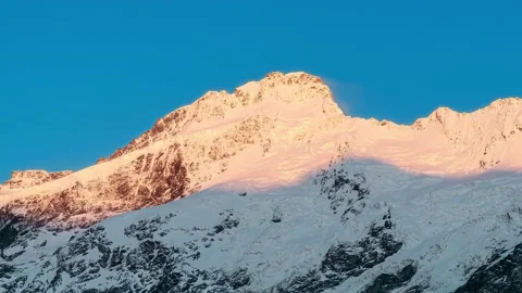Time-lapse, sunlight and shadow moving on snow-capped mountain under blue sky Stock Footage 159575951