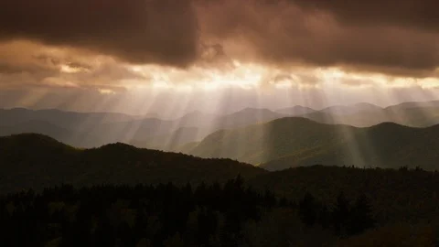Time-lapse of sunrays falling on the mountain ranges through the dark clouds Stock Footage 103395607