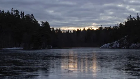 Time-lapse of sunrise and clouds moving, with light reflecting on the ice of Stock Footage 98888402