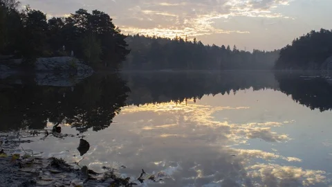 Time-lapse of sunrise with clouds mirrored in a forest lake. Stock Footage 96288721