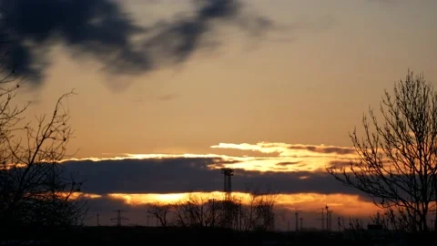 Time lapse sunrise. Trees, power poles, wind turbines. Sun flash. Sky, clouds. Stock Footage 152160139