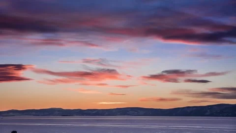 Time lapse sunset cloudy sky on background frozen Lake Baikal, cloud move winter Stock Footage 317302628