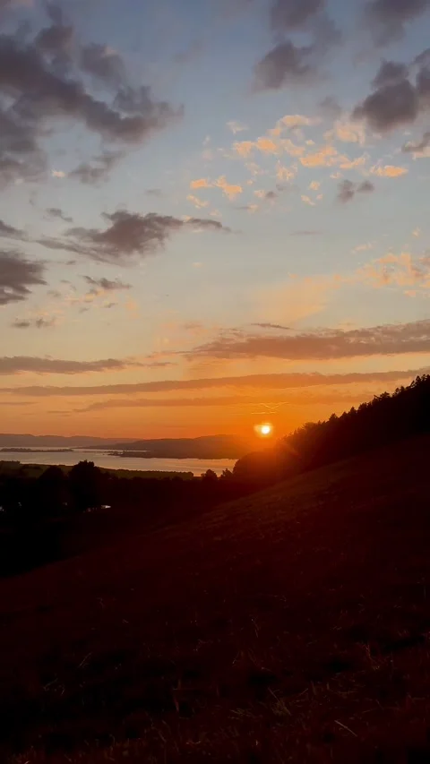 Time-lapse sunset with fast moving clouds over hills and lake Video stock 318075642
