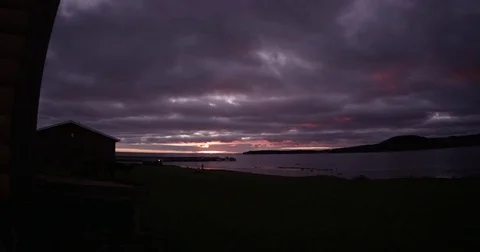 Time-lapse sunset over ocean inlet with cottage on shore Stock Footage 82072991