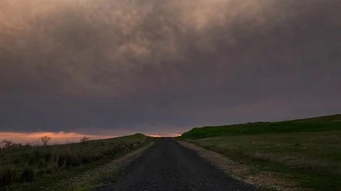 Time Lapse of Sunset Over Rural Country Road Between Two Green Fields Stock Footage 106157381