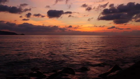 Time lapse sunset on Patong Beach. Waves crash against large rocks Stock Footage 145437158