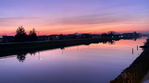 Time lapse: sunset reflections in the river with fast speeding cars on river dam Stock Footage 231349433