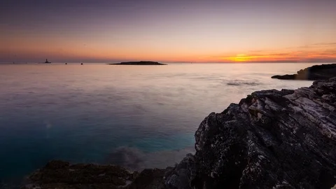 Time Lapse - Sunset at the rocks of a beach with the moving water Stock Footage 99368408