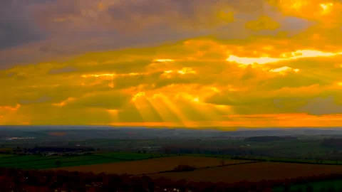 Time lapse sunset sky with rain clouds moving and golden sun rays over Video stock 332219165