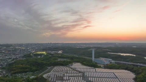 Time Lapse: Sunset on solar panels at green energy farm as city lights up Stock Footage 239785229