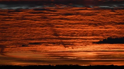 Time lapse sunset of spectacular moving orange and gray clouds above a distant h Stock Footage 288011616