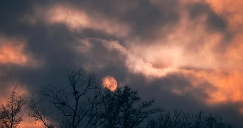 Time-lapse Sunset Sun Behind Dark Gray Clouds Moving Fast. Round Solar Disk 4K Stock Footage 122978556