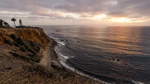 Time Lapse - Sunset with a view over the beach and a cliff with a lighthouse a Stock Footage 99366021