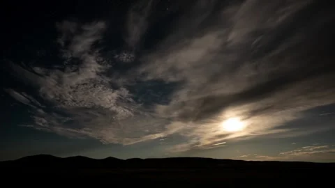 Time lapse of thin clouds moving through the night sky in front of a full moon.  Stock Footage 281184532