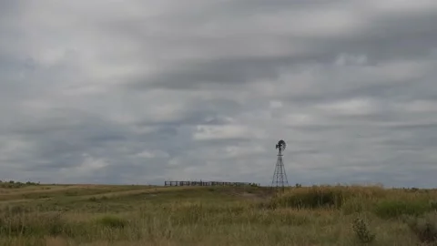 Time lapse of a traditional ranch windmill and clouds above a prarie grassland Видео 133816615