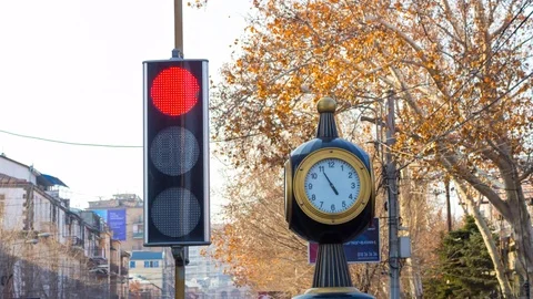 Time lapse: traffic lights with a clock on the city background with trees Stock Footage 75357228
