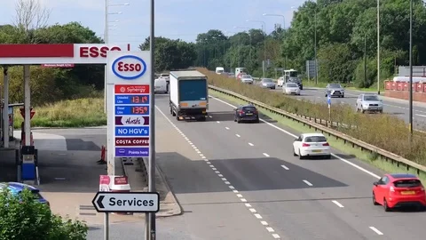 Time lapse traffic passing advert of fuel prices on petrol station forecourt uk Stock Footage 113454501
