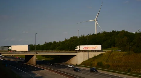 Time lapse traffic passing electricity generating windmills motorway leeds uk Stock Footage 66534311