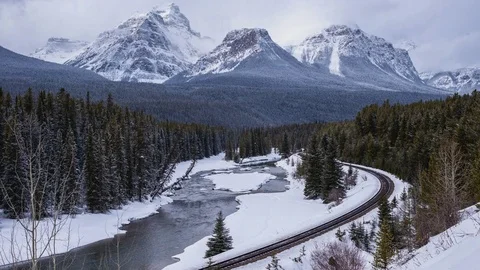 Time lapse of train tracks next to river in the mountains with snow falling Stock Footage 72740699