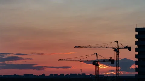 Time lapse. Two cranes are working after the sun is setting behind the horizon Stock Footage 313954356