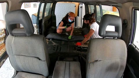 Time lapse two people removing carpet from the floor of a camper van Stock Footage 172081427