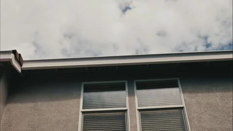 Time lapse of Two windows and a rooftop on a modern stucco home Stock Footage 314468912