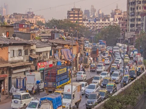 Time lapse of vehicles passing on a busy road alongside slums, Mumbai, India Stock Footage