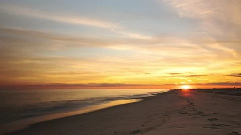 Time lapse of a vibrant sunset over a beach with waves coming in Stock Footage 195841483